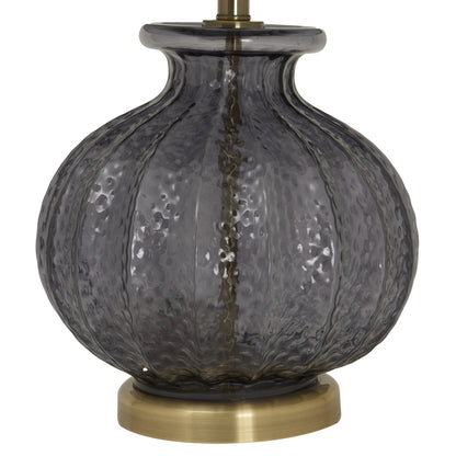 Decorative lamp with textured glass shade and brass base on a white background