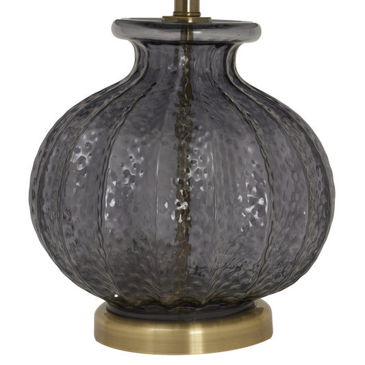 Decorative lamp with textured glass shade and brass base on a white background