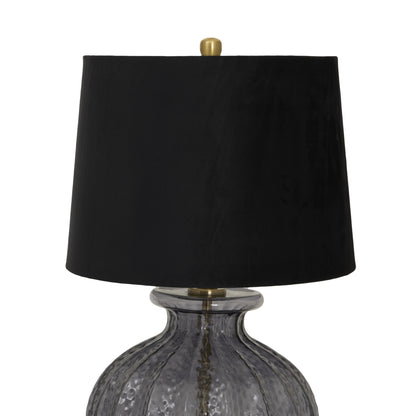 Table lamp with black shade and textured glass base on a white background