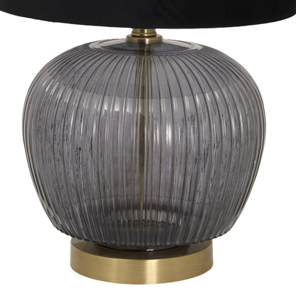 Table lamp with ribbed glass shade and brass base on a white background