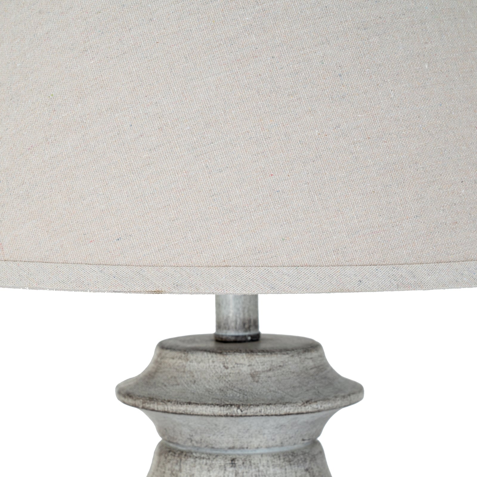 Close-up of a lamp with a textured base and light gray fabric shade on a white background