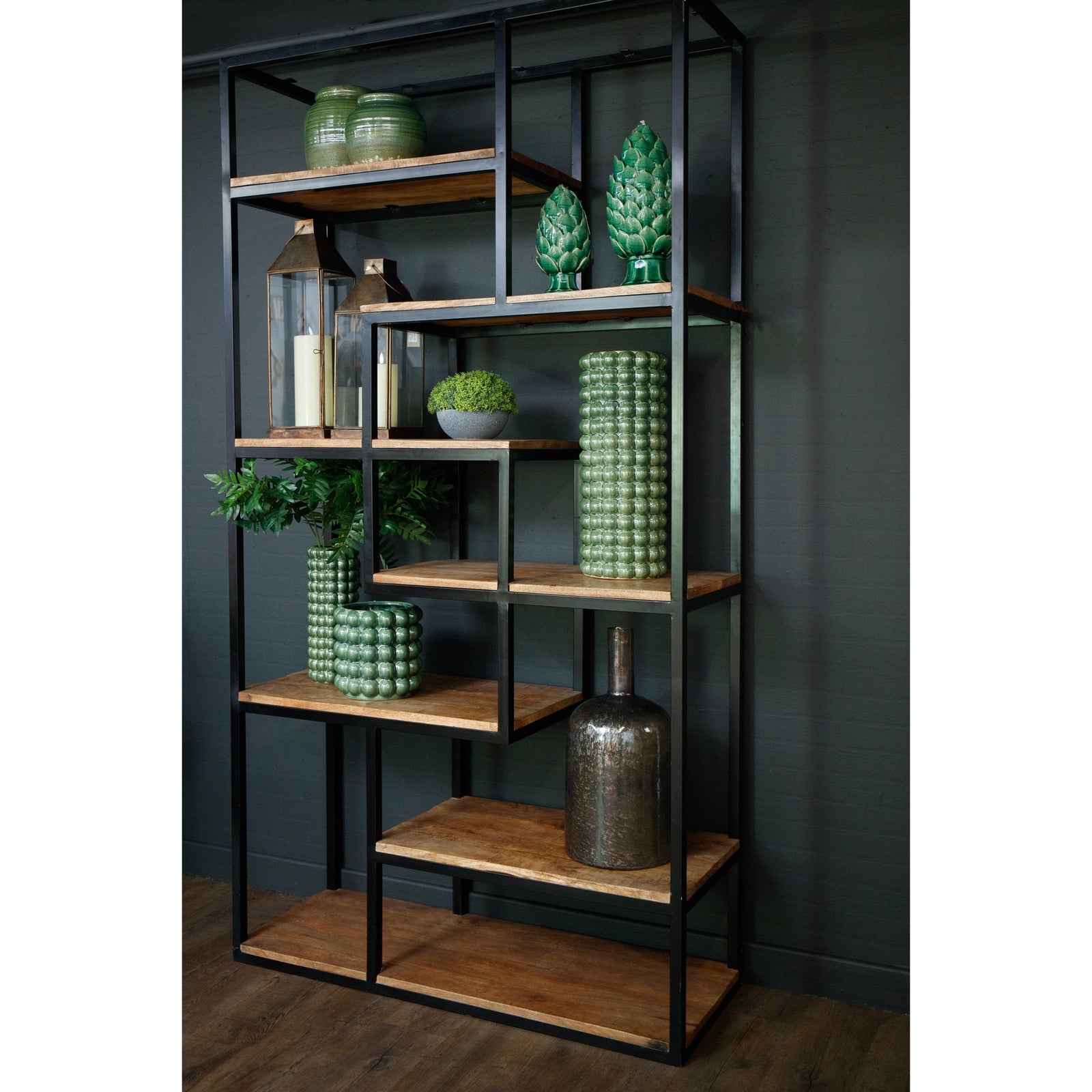 Bookshelf with wooden shelves and decorative items against a dark wall