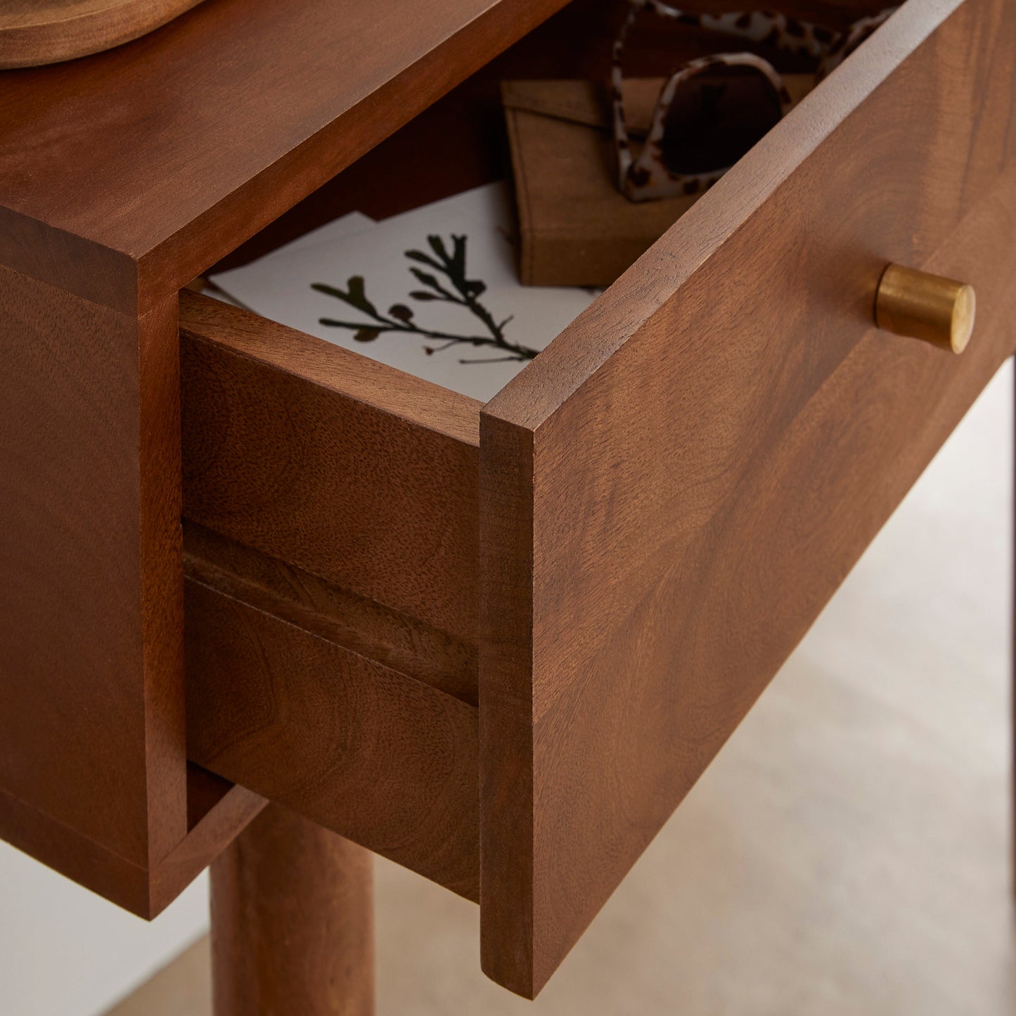 Wooden drawer with a gold handle on a light-colored surface