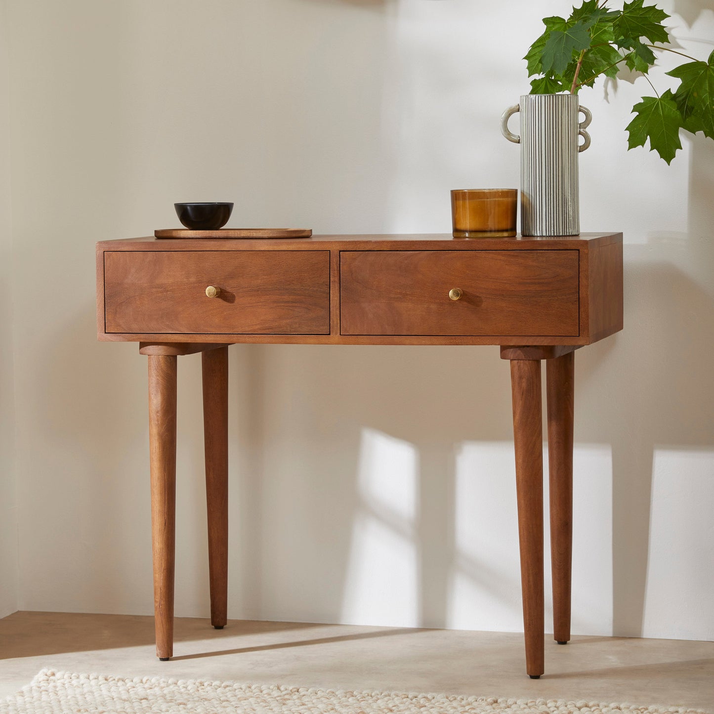 Wooden console table with two drawers against a plain wall.