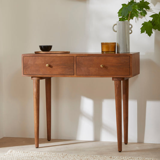 Wooden console table with two drawers against a plain wall.