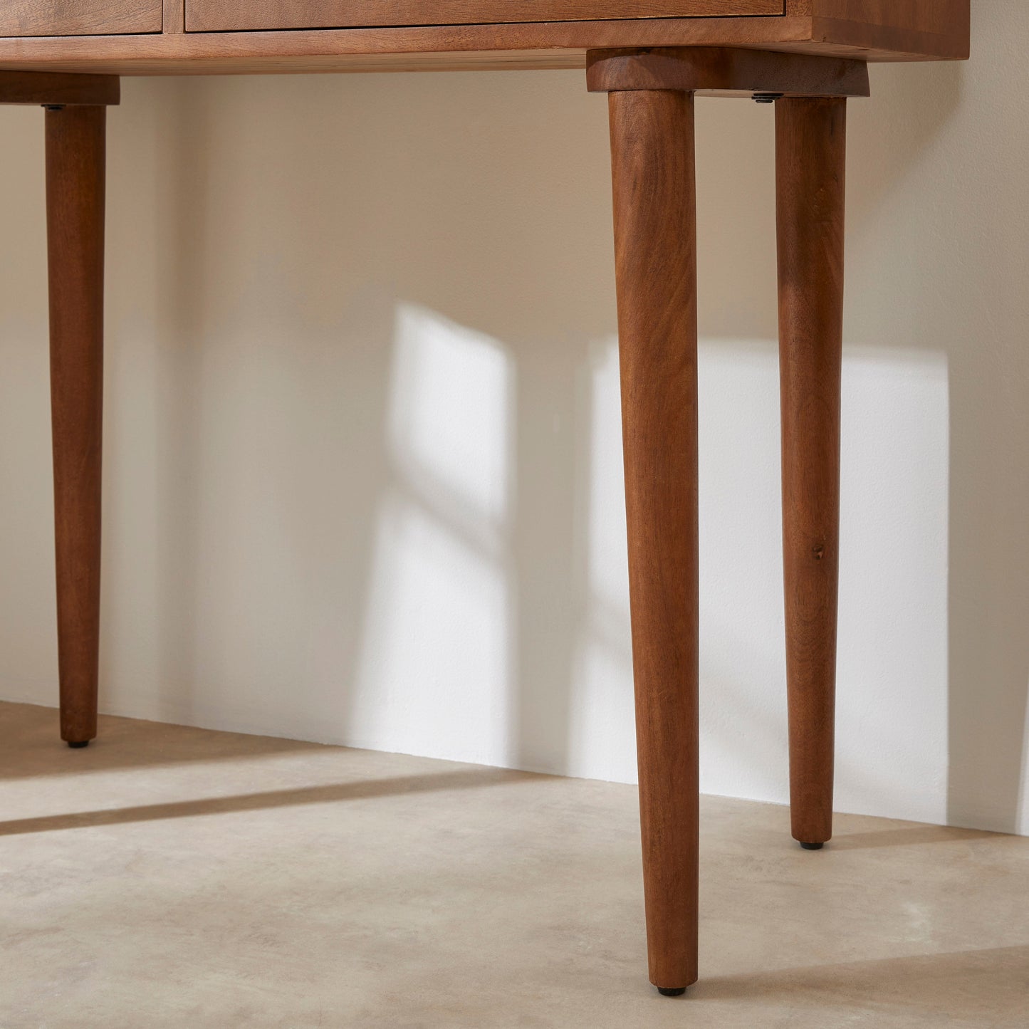 Wooden desk with a focus on its legs against a neutral background