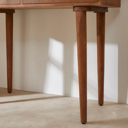 Wooden desk with a focus on its legs against a neutral background