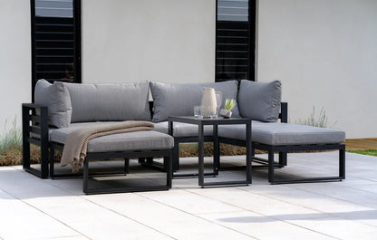 Outdoor patio furniture set with gray cushions and a small table on a patio.