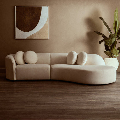 Beige sofa with decorative cushions in a room with a painting and plant on a brown wall.