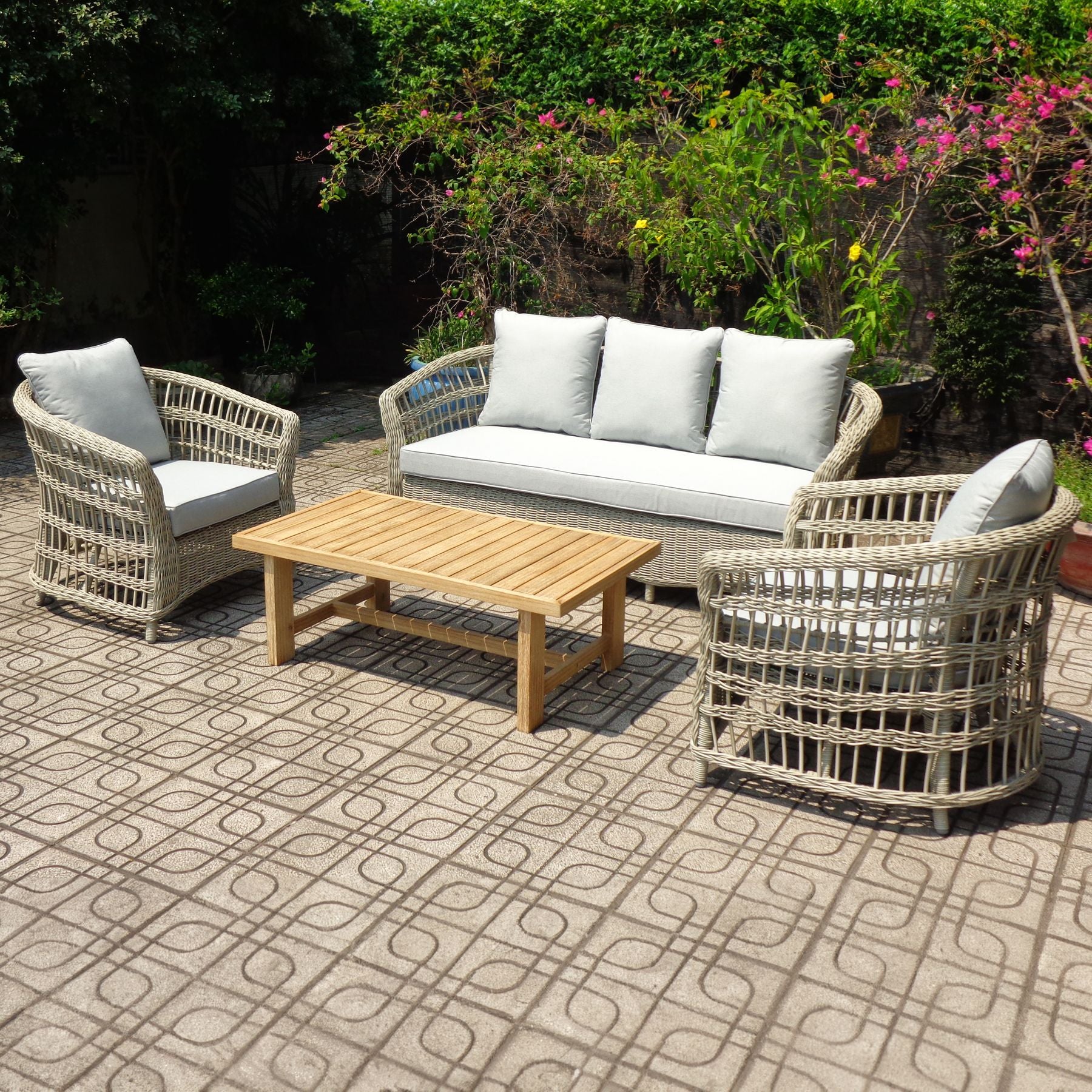 Outdoor patio set with wicker chairs, sofa, and table on a patterned patio.