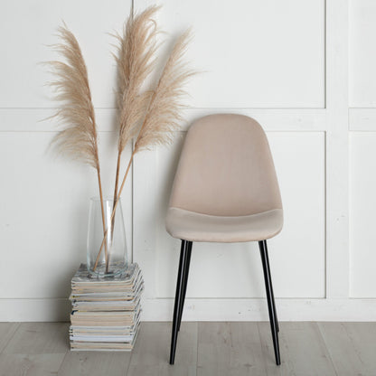 Beige chair next to a vase with pampas grass against a white wall.