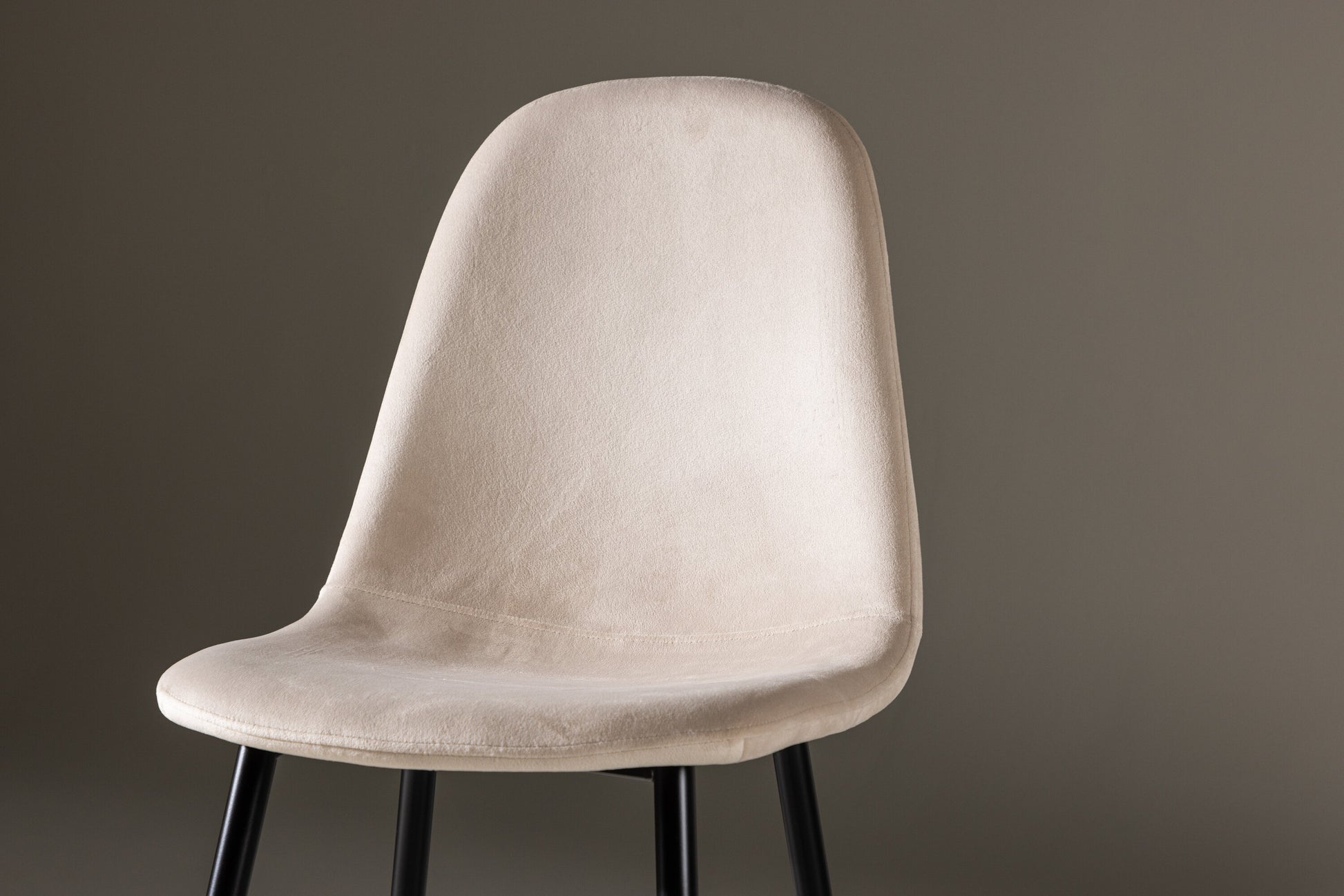 Beige chair with black legs on a brown background