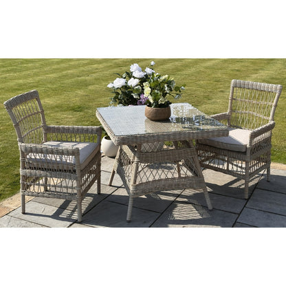 Outdoor patio set with wicker table and chairs on a patio with grass background