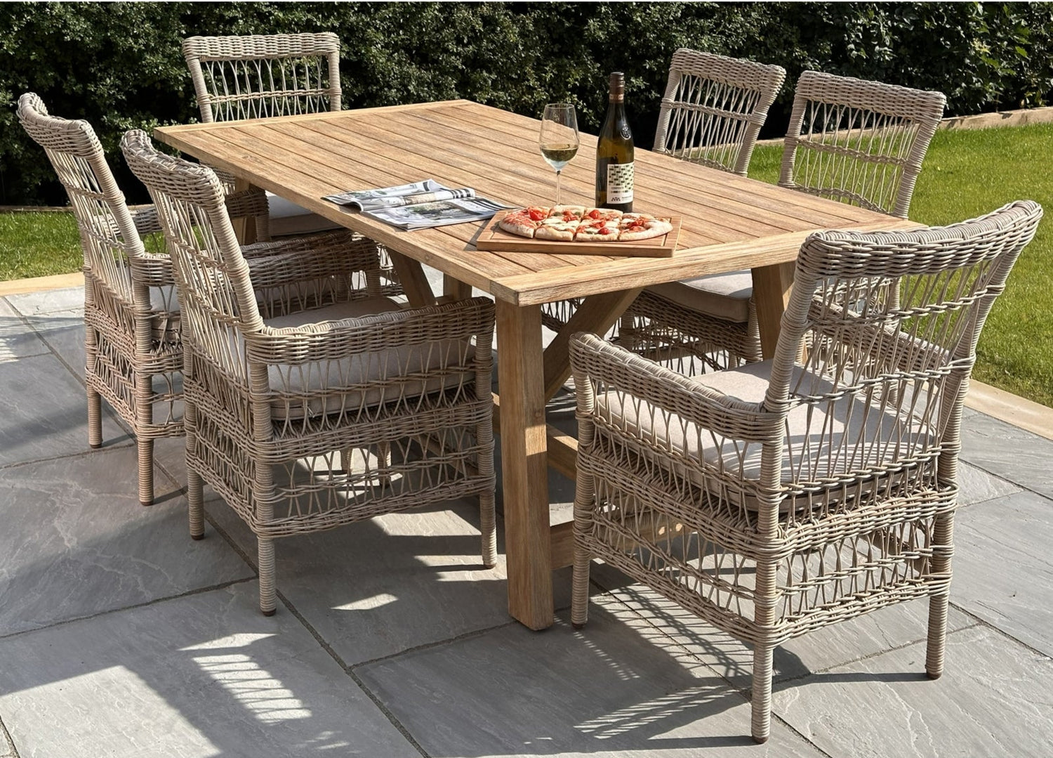 Outdoor dining setup with a wooden table and wicker chairs on a patio.