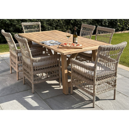 Wooden outdoor dining table with six wicker chairs on a patio.