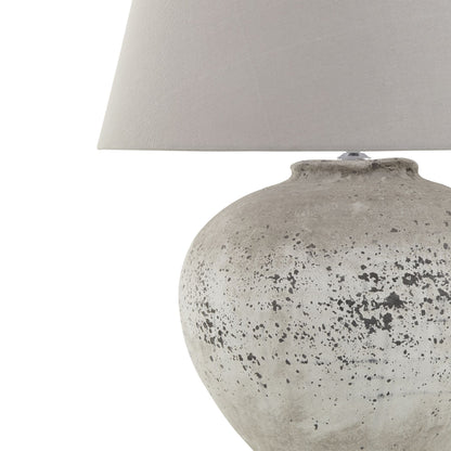 Table lamp with textured gray base and white lampshade on a white background