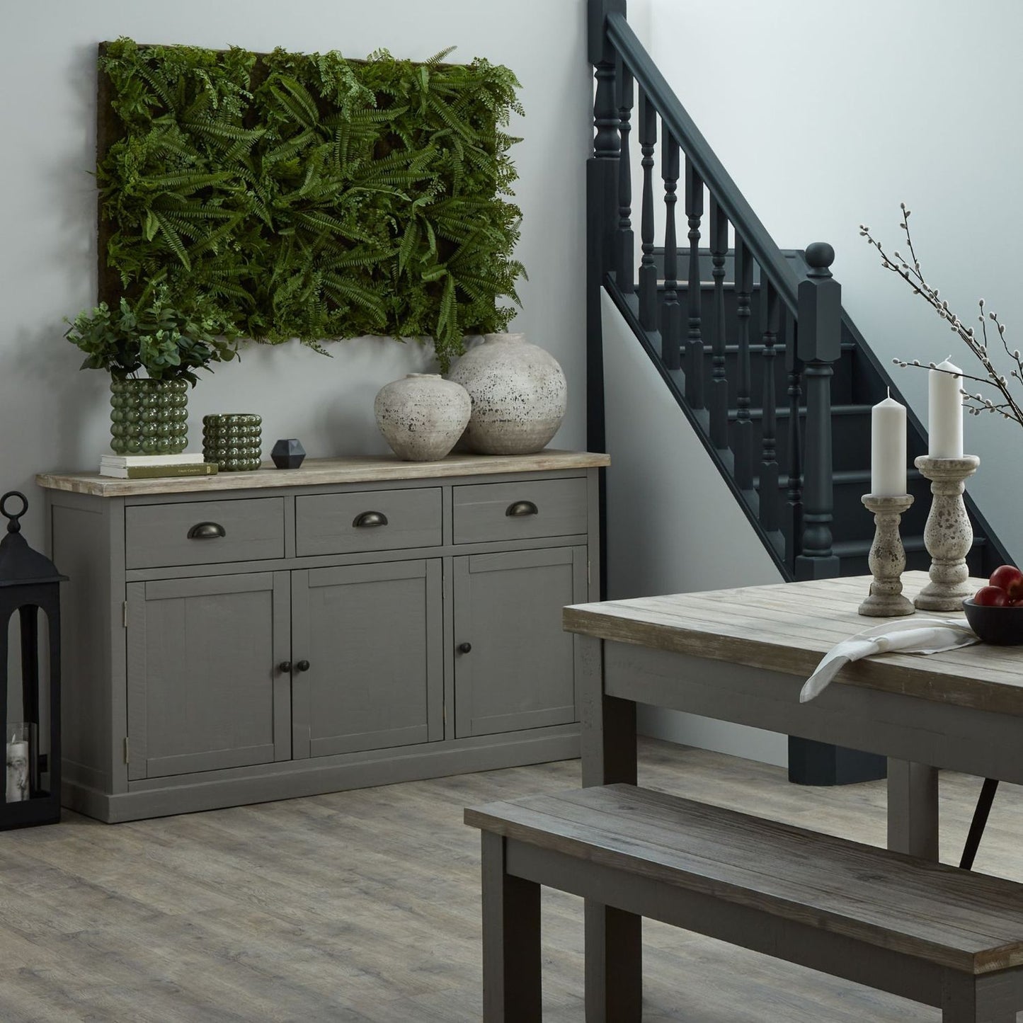 Gray sideboard with decorative items in a room with a staircase and wooden table.