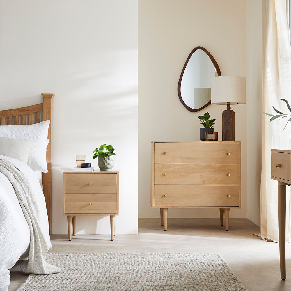 Wooden bedroom furniture including a bed, nightstands, and a dresser in a well-lit room.