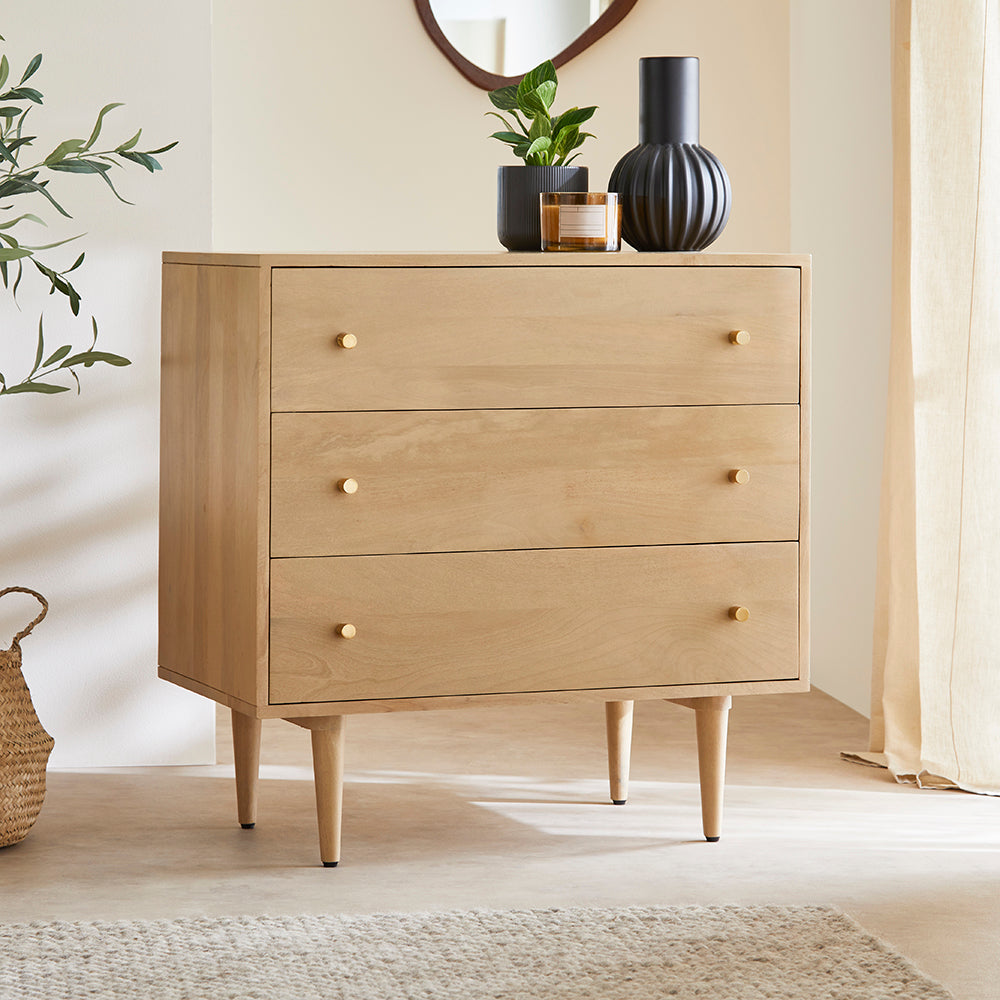 Wooden dresser with three drawers in a room with a plant and vase on top
