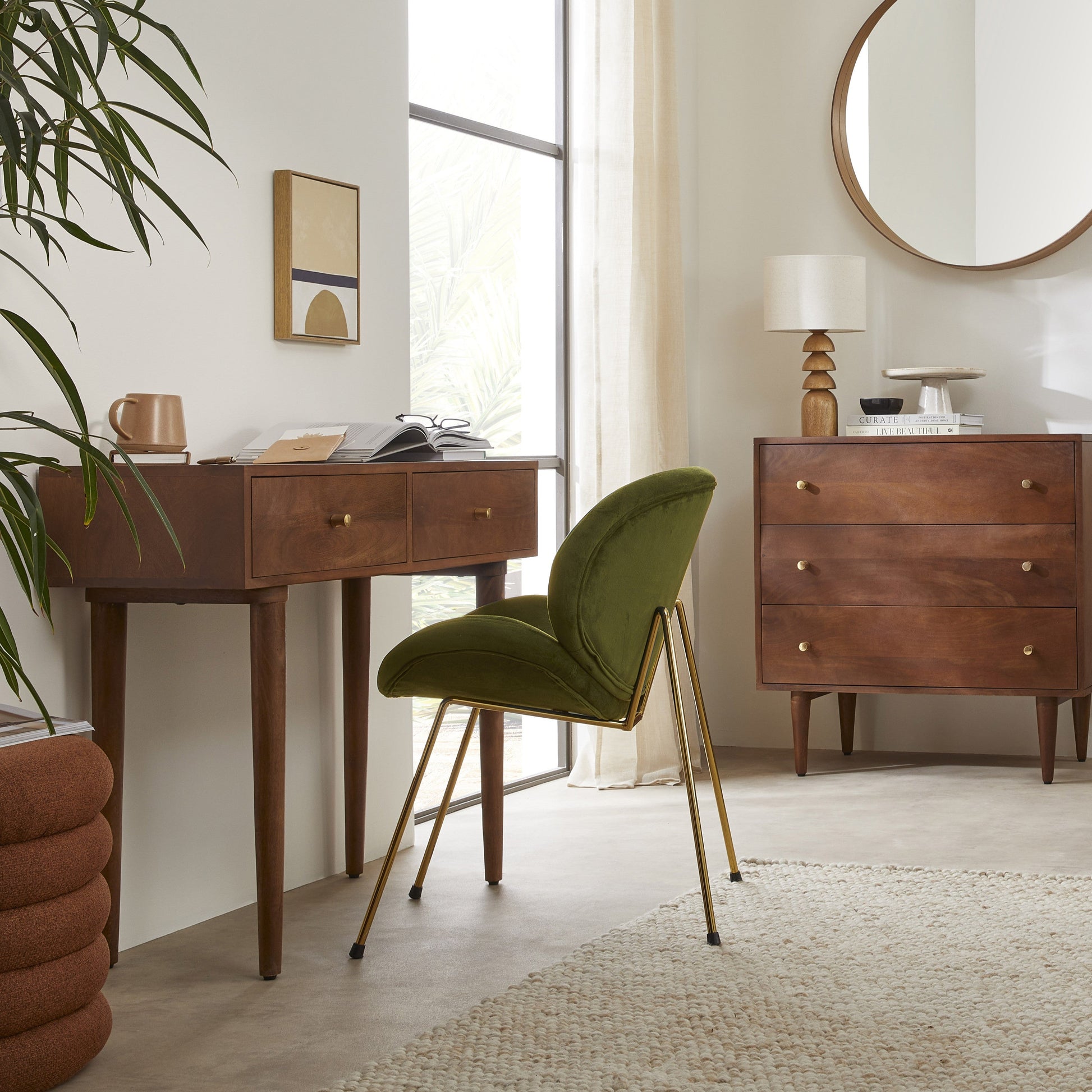 Modern interior with wooden desk, green chair, and round mirror.