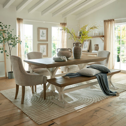 Dining room with wooden table, chairs, and bench on a patterned rug.