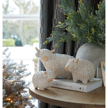 Decorative sheep figurines on a book with a Christmas tree in the background