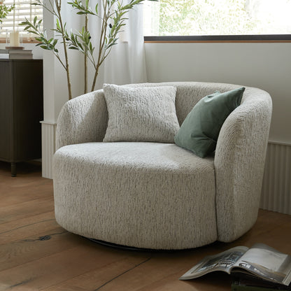 Beige armchair with green pillow in a room with wooden floor and plant