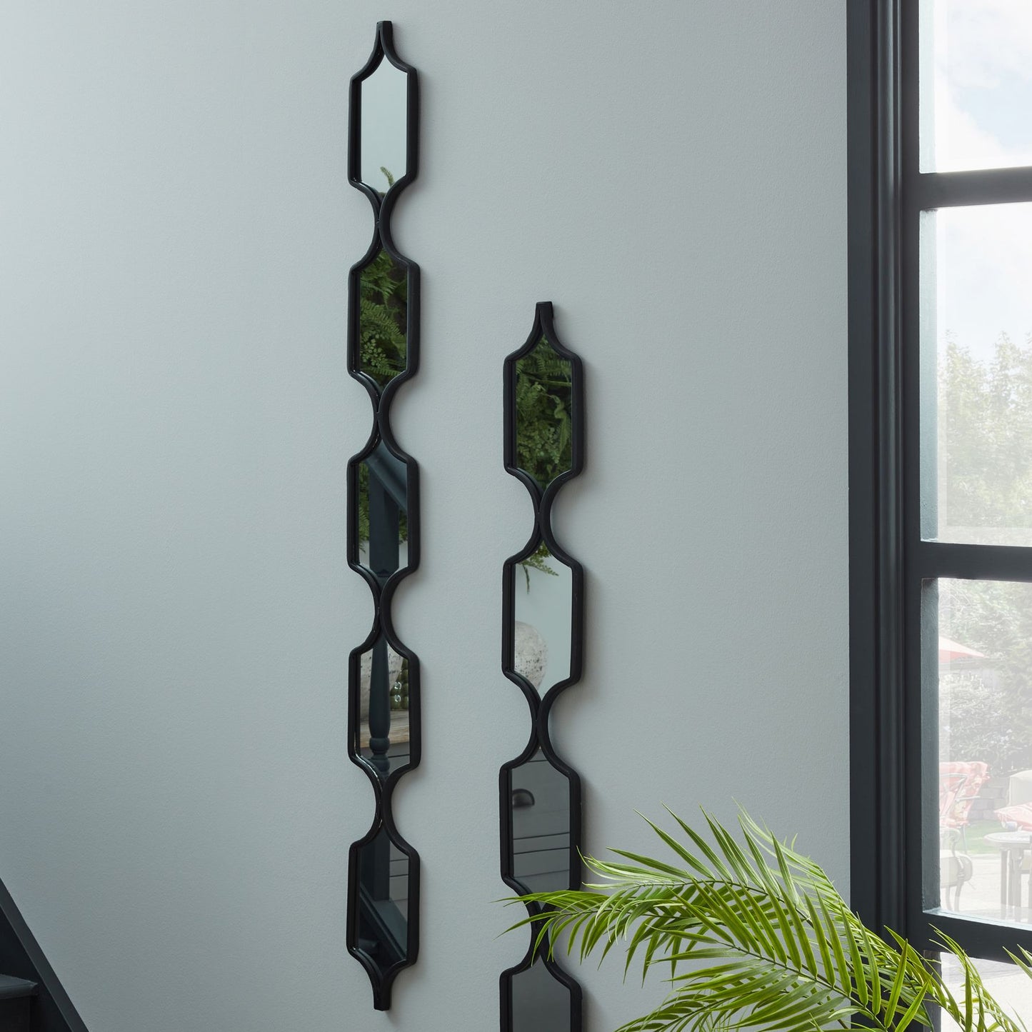 Decorative wall mirrors with geometric design on a light gray wall.