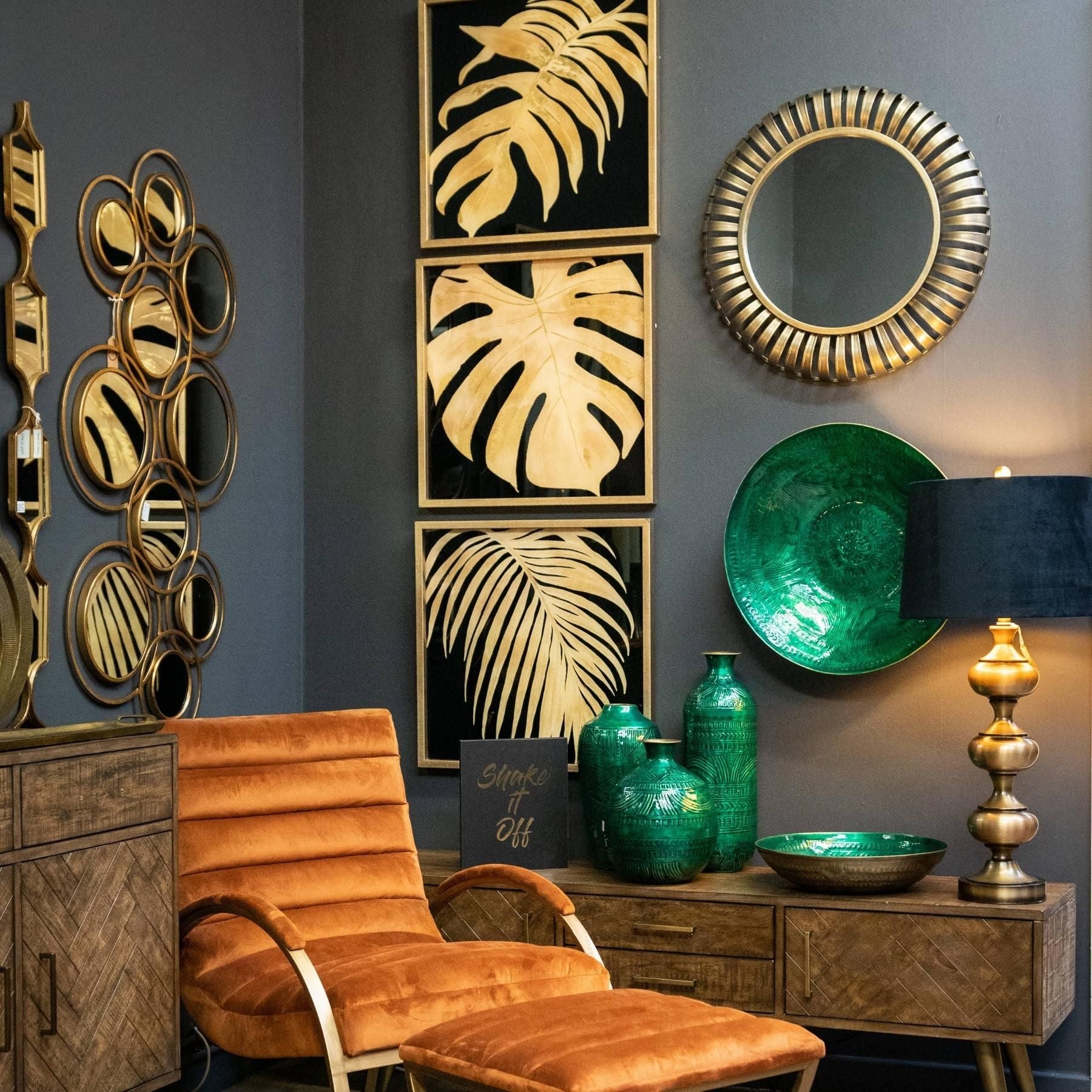Decorative interior with gold leaf wall art, a brown chair, and green vases against a gray wall.