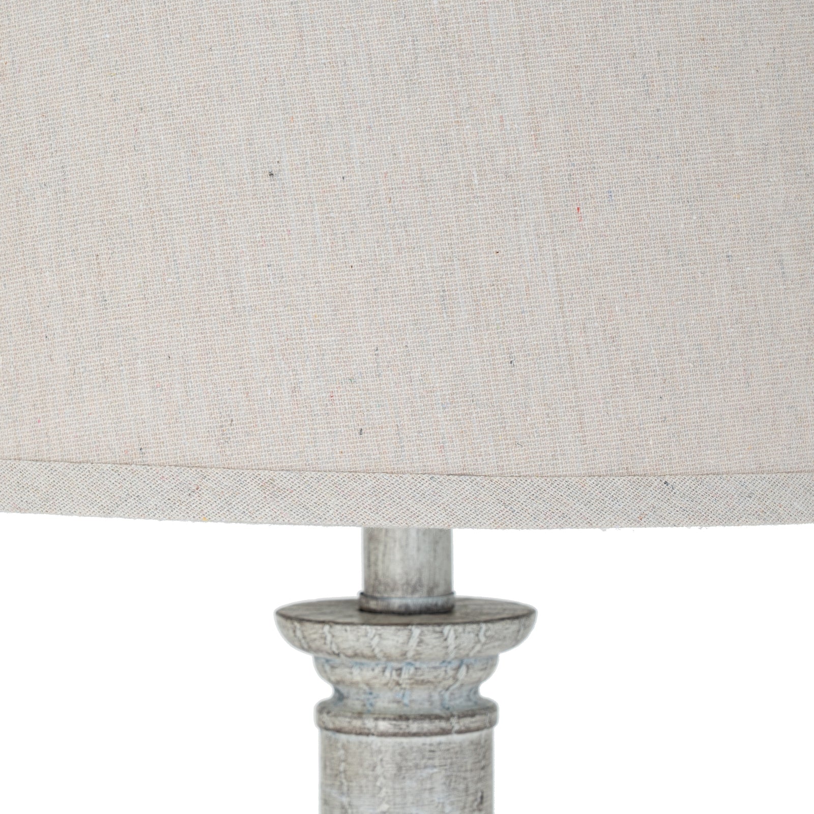 Close-up of a lamp with a textured beige shade and metallic base on a white background