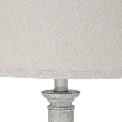 Close-up of a lamp with a textured beige shade and metallic base on a white background