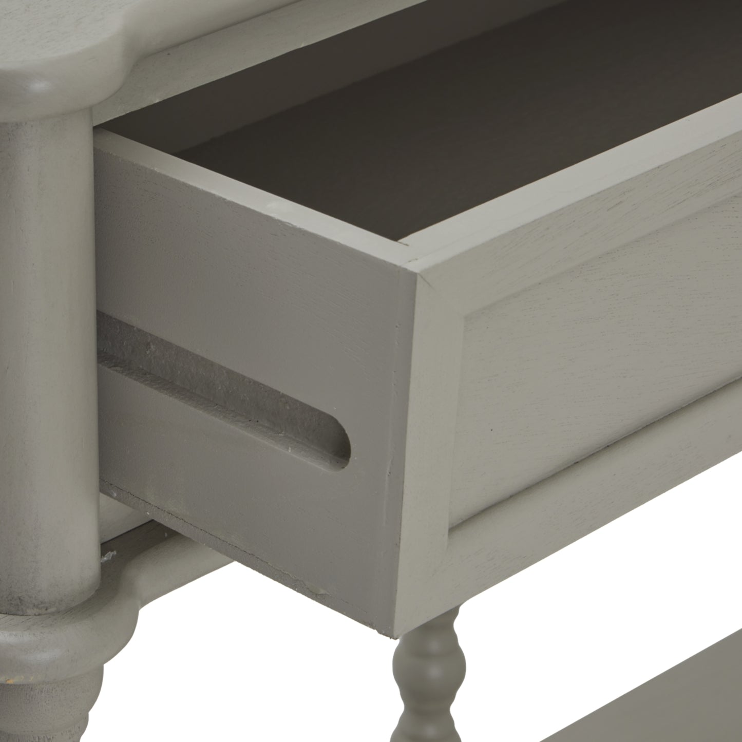 Close-up of a gray wooden drawer with a white pedestal table in the background.