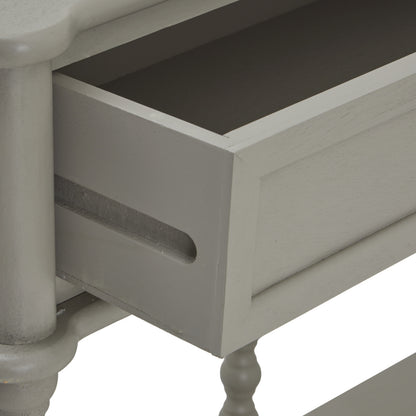 Close-up of a gray wooden drawer with a white pedestal table in the background.