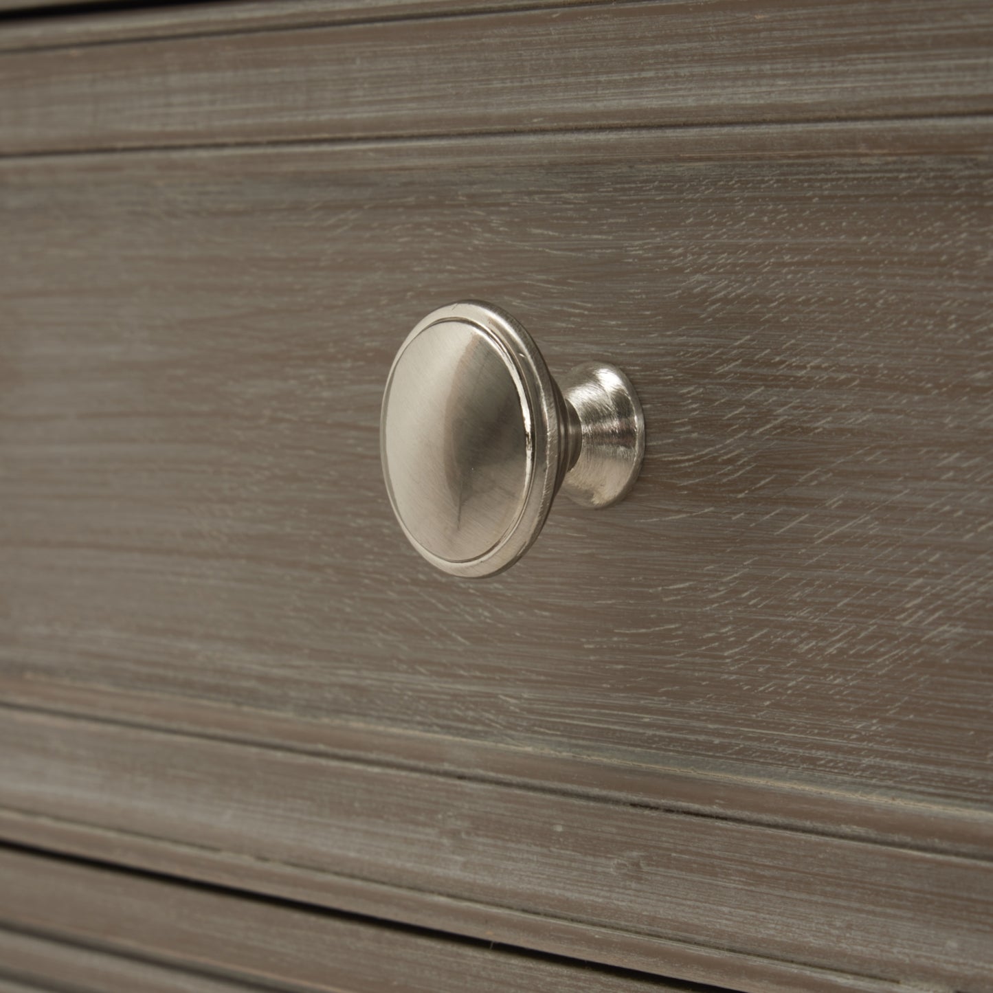 Metallic cabinet knob on a wooden drawer
