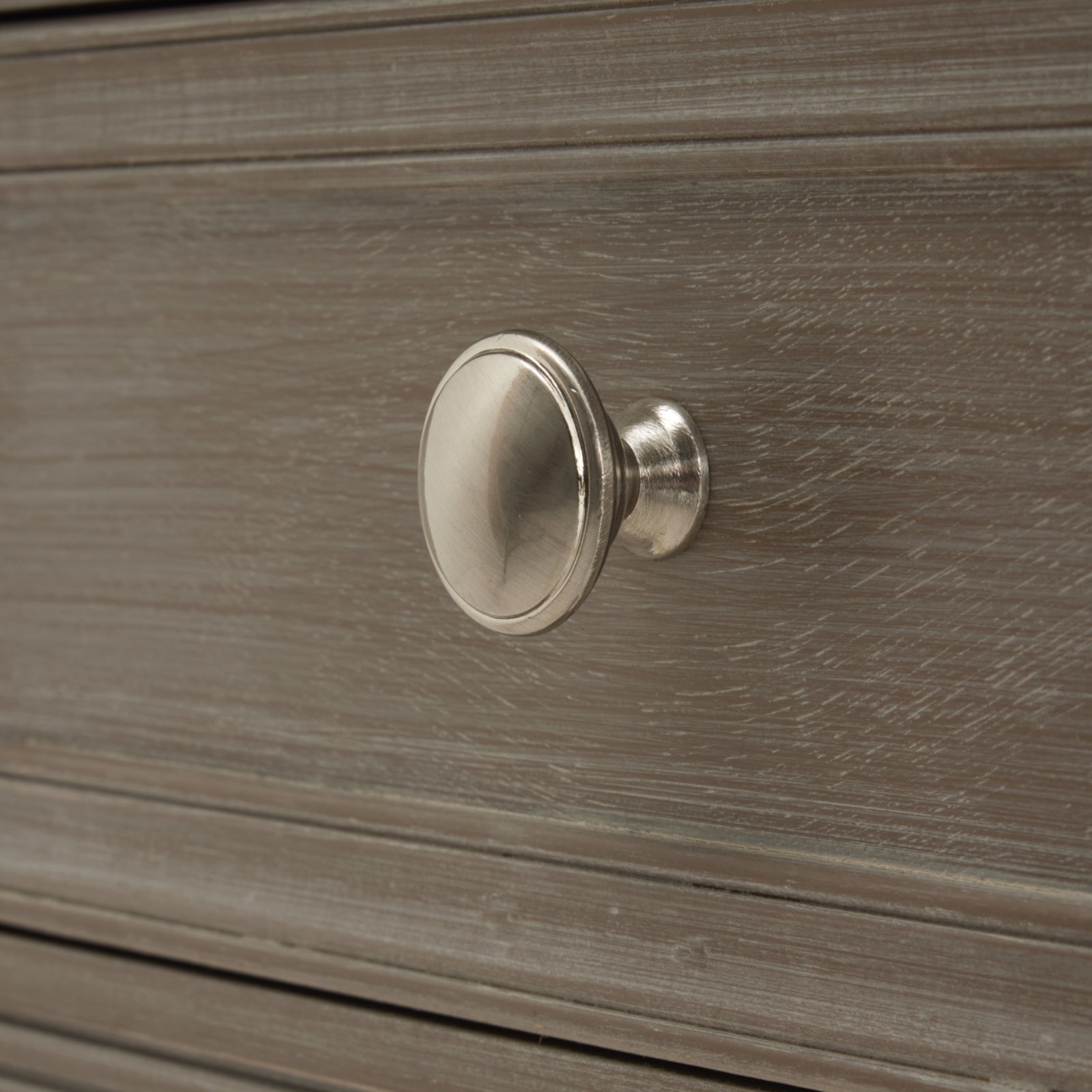 Metallic cabinet knob on a wooden drawer
