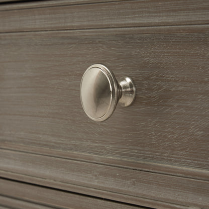 Metallic cabinet knob on a wooden drawer