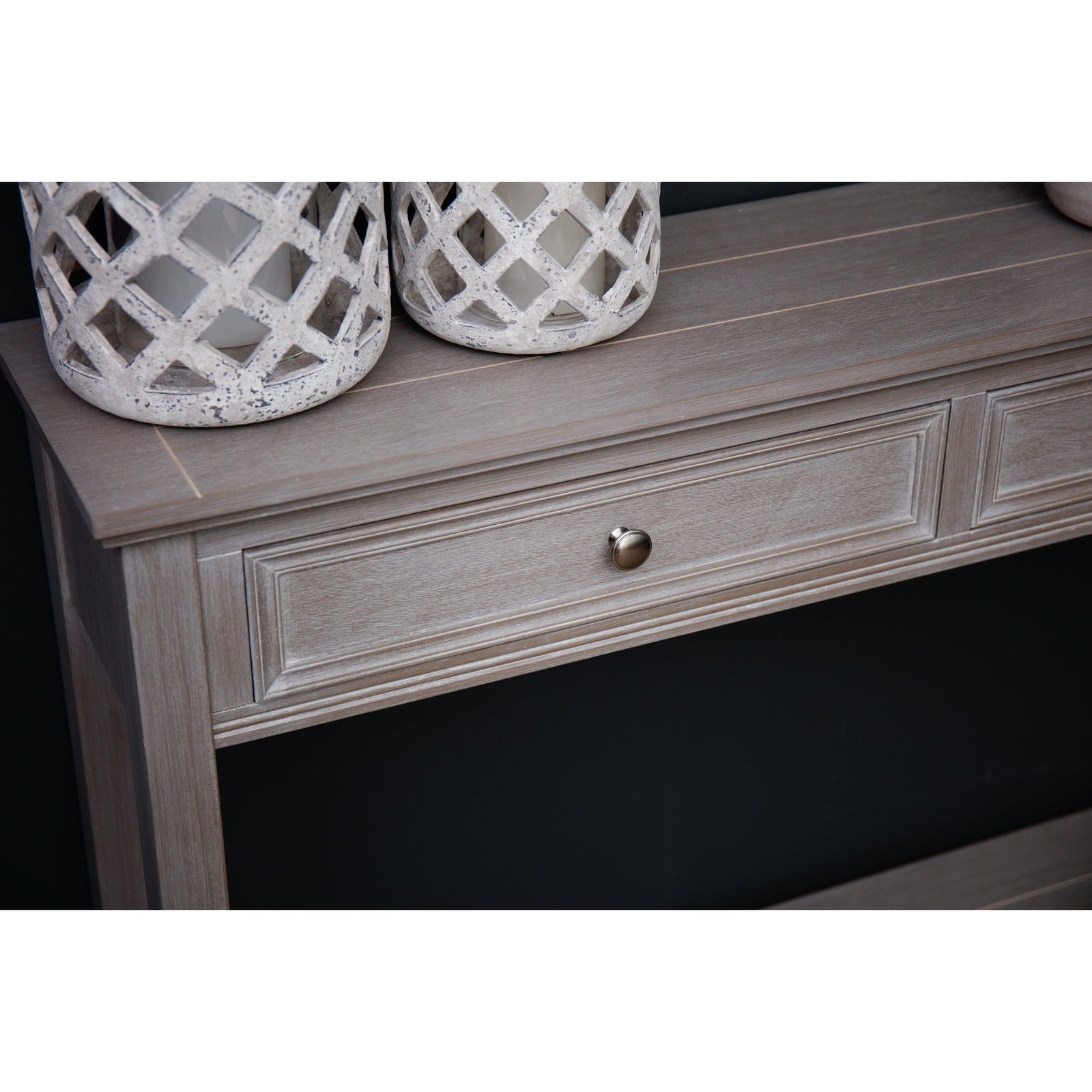 Wooden console table with a drawer and decorative items on top against a black background