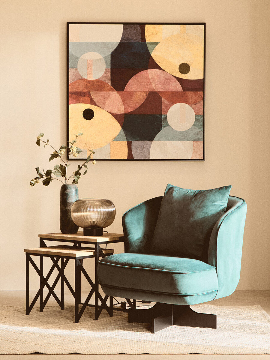 Modern living room with a teal armchair, side table, and abstract wall art.