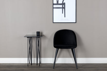 Black chair and small table against a gray wall with a framed picture.