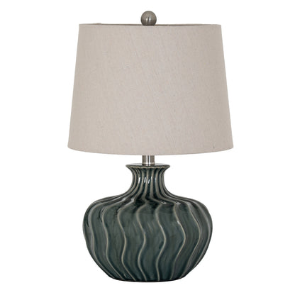 Table lamp with a textured green base and beige lampshade on a white background