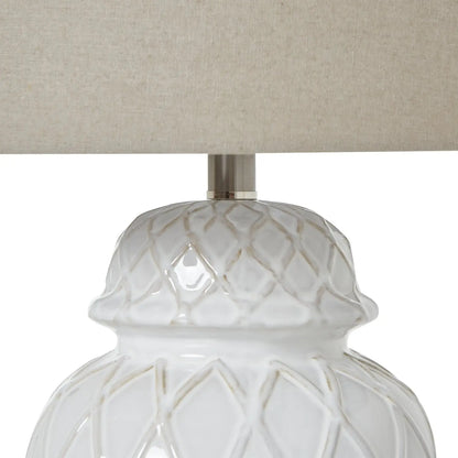 Close-up of a white textured lamp base with a beige lampshade on a white background