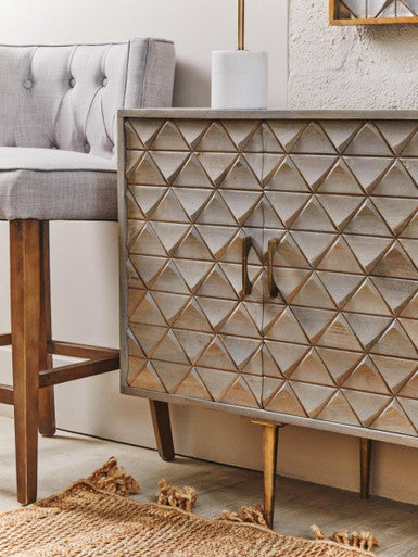 Wooden sideboard with geometric pattern in a room with a gray chair and textured rug.