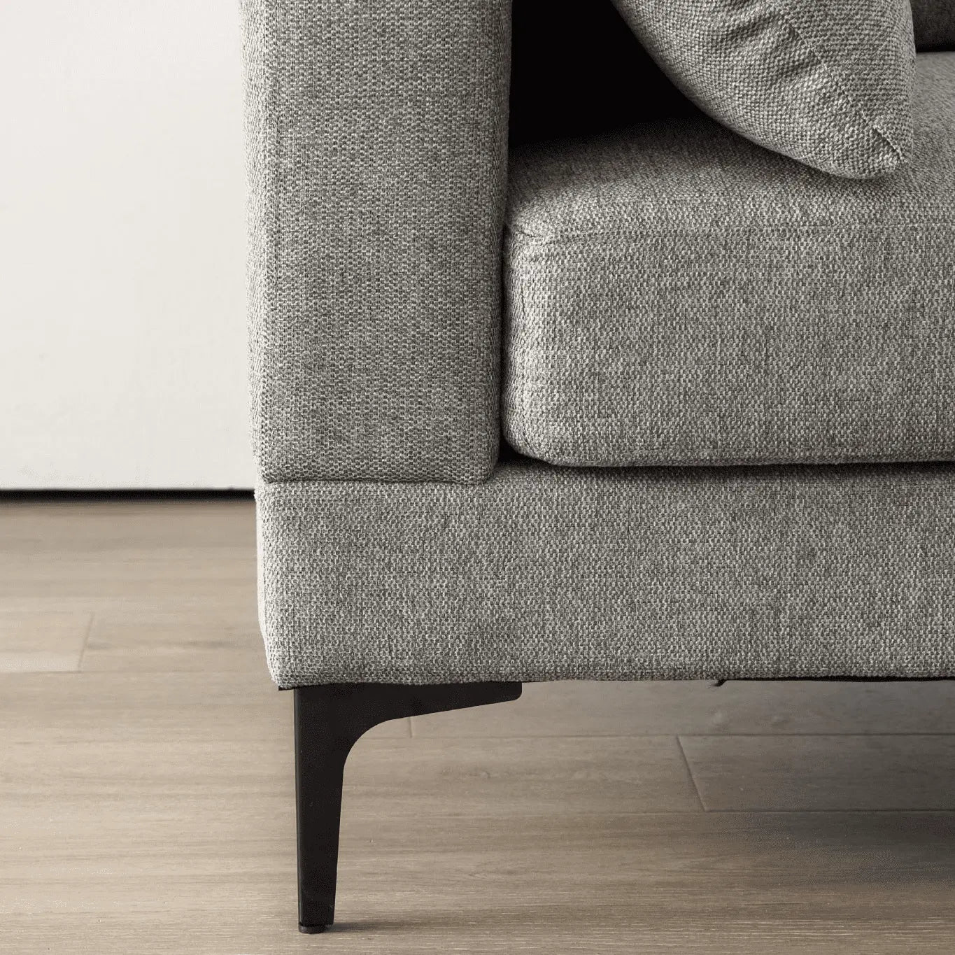 Gray sofa with a textured fabric finish on a wooden floor.
