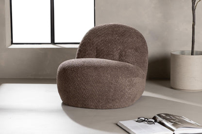 Brown textured armchair in a modern room with a window and plant.