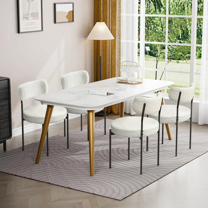 Dining room with a white table and chairs near a large window with a view of greenery.