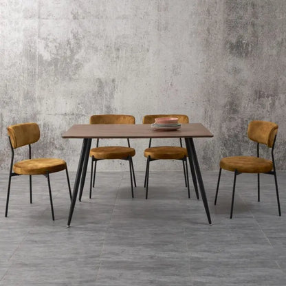 Dining table with four chairs against a gray concrete wall.