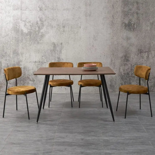 Dining table with four chairs against a gray concrete wall.