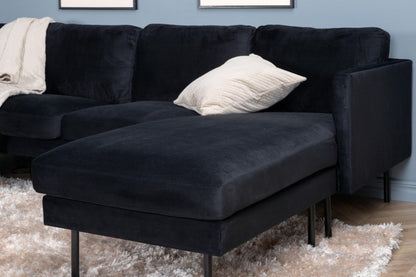 Black sectional sofa with a beige pillow on a textured rug