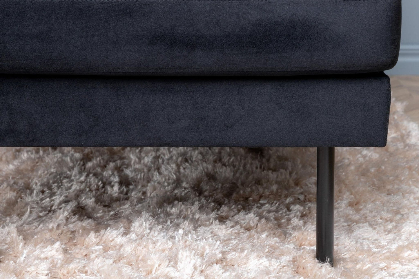 Navy blue sofa with a visible leg on a beige carpet