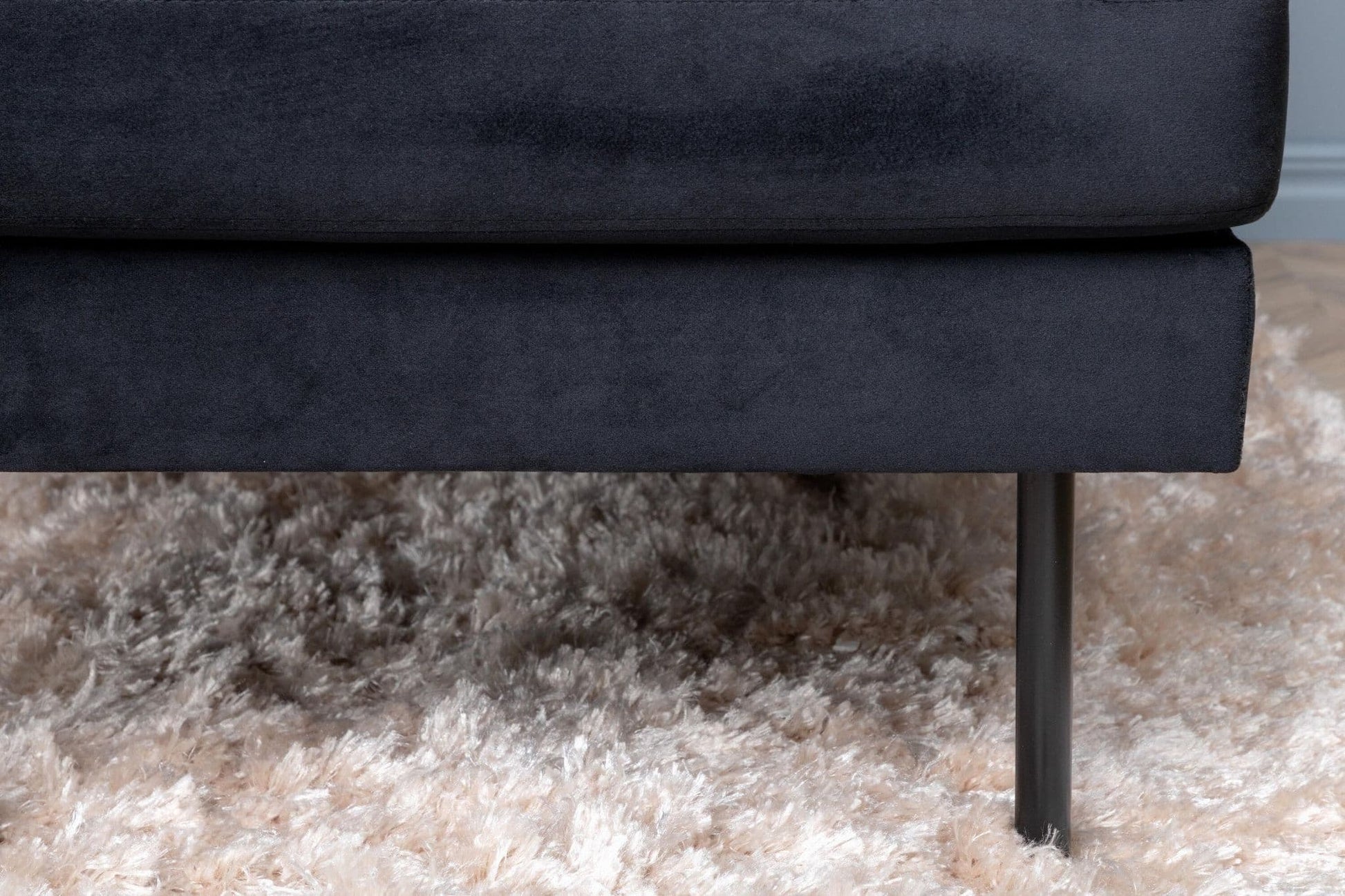 Navy blue sofa with a visible leg on a beige carpet